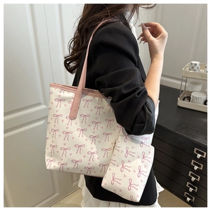 Detail of printed tote bag with pink bow pattern and matching small pouch on shoulder