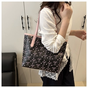 Detail of black tote bag with pink bow pattern and premium leather straps