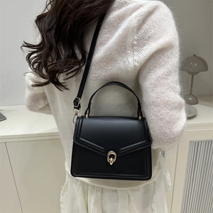 Sac à bandoulière noir minimaliste avec fermoir doré et finition mate structurée