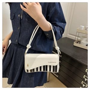 Detail of white piano key bag featuring music notes and I LIKE MUSIC print details