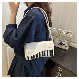 Detail of piano key design shoulder bag featuring I LIKE MUSIC gold lettering and note