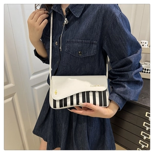 Detail of white PU crossbody bag featuring piano key pattern and I LIKE MUSIC print