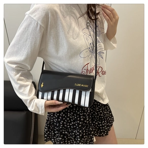 Detail of black piano keyboard shoulder bag with I LIKE MUSIC print and gold musical notes