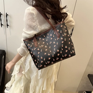Sac fourre-tout noir avec imprimé cerises et anses marron porté par un mannequin