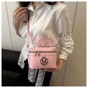 Pink minimalist box handbag with gold M logo shown being carried by a model
