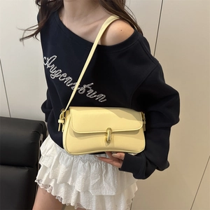 Sac sous le bras minimaliste jaune pâle avec boucle dorée porté par un mannequin