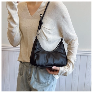 Detail of black crescent shoulder bag with knot strap and metallic silver bead accents