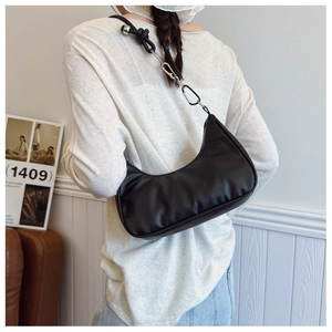 Detail of a black crescent underarm bag with metal carabiners and thick knotted strap