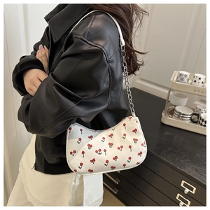 Detail of white hobo bag with red cherry prints and silver chain shoulder strap