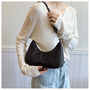 Close-up of a black crescent hobo shoulder bag with zipper and metallic strap hardware