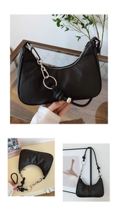 Detail of black crescent shoulder bag featuring silver metal rings and knotted rope strap