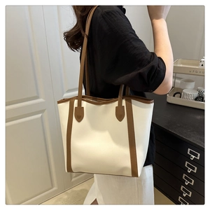 Detail of white tote bag with brown leather trim shown on model for daily commuting