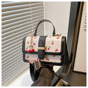 Detail of printed leather crossbody bag with cherry pattern and gold buckle closure