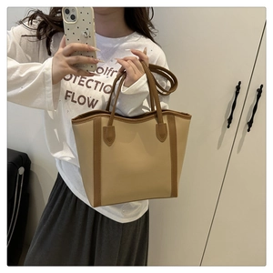 Detail of cream and brown tote bag showing dual handles and adjustable shoulder strap