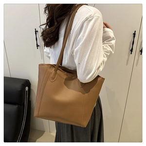 Brown leather tote bag shown on model highlighting spacious capacity and shoulder strap