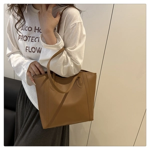 Brown leather tote bag side view on model showing medium size and crossbody style