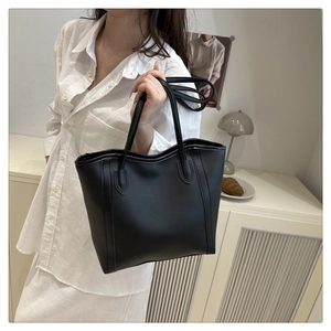 Minimalist black tote bag with long handles and fine stitching shown in lifestyle setting