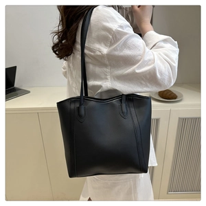 Modern black minimalist tote bag worn by model in a stylish office commuter setting