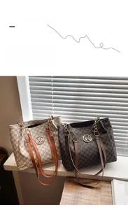 Detail view of large tote bags with M-pattern print and chain straps on a wooden table
