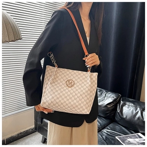Fashion tote bag with 'M' logo print and metal chain strap worn by a model in a studio