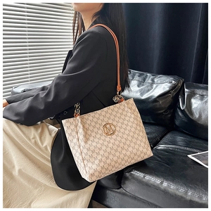 Detailed view of tote bag with vintage monogram pattern and gold metal logo charm