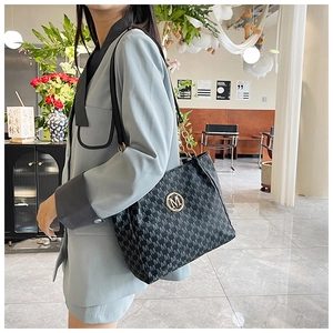 Close-up of black jacquard tote bag with golden M logo and metal chain strap detail