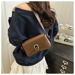 Detailed close-up of dark brown leather crossbody bag with elegant golden clasp lock