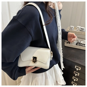 Détail d'un sac bandoulière blanc minimaliste en cuir avec fermoir rotatif doré élégant