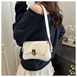 Detail of white glossy leather underarm bag featuring a dual-tone black gold twist lock