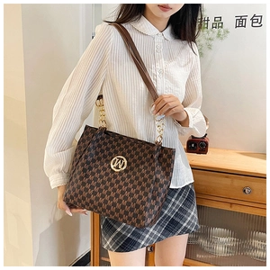 Detail of dark brown tote bag featuring classic M monogram and gold metal buckle on front