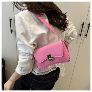 Pink shoulder bag with golden lock shown on model to highlight size and fit