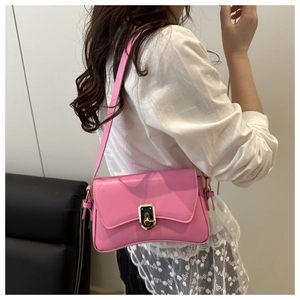 Détail d'un sac bandoulière en cuir rose avec fermoir en métal doré porté par un mannequin