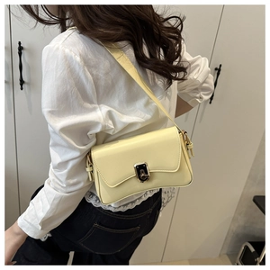 Close-up of a pale yellow leather shoulder bag featuring a sleek metal twist lock buckle
