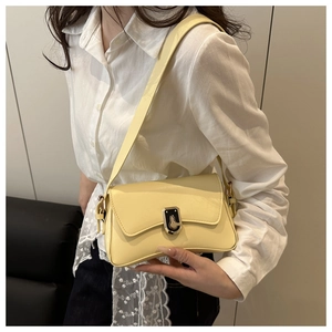 Detail of light yellow matte leather shoulder bag with unique metal buckle on model