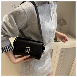 Détail du sac à bandoulière noir avec rabat ondulé et fermoir en métal doré chic