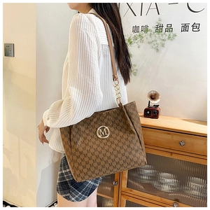 Brown vintage tote bag with letter M print, gold chain detail and logo in a cafe setting