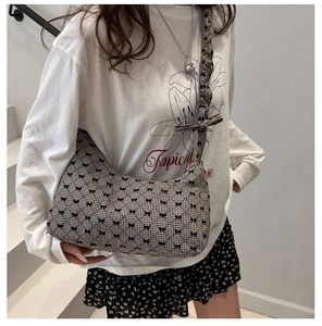 Close-up of houndstooth hobo bag featuring black bow details and ruffled shoulder strap