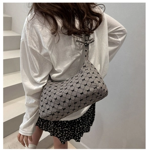 Detail of checkered shoulder bag featuring black bows on a minimalist white background