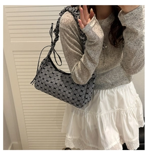 Detail of gingham shoulder bag featuring black bows and ruffled strap on model