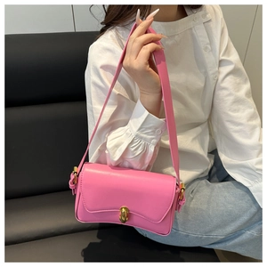 Detail of pink leather handbag with gold metal twist lock shown in lifestyle setting