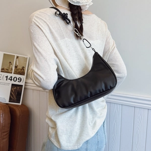 Black matte leather hobo bag with knotted strap and silver rings worn by a model