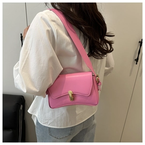 Detail of hot pink shoulder bag featuring a gold U-shaped lock and adjustable strap