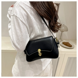 Chic black shoulder bag with gold oval twist lock closure shown in a lifestyle setting