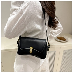 Detail of minimalist black matte leather shoulder bag with golden metal turn-lock clasp
