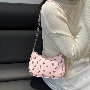 Pink hobo bag with cherry print and silver chain strap shown on model's shoulder