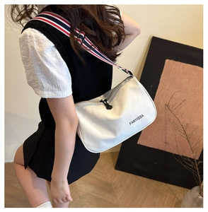Detail of white canvas crossbody bag with striped wide strap and Fanyissa logo