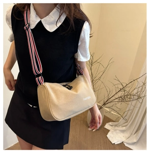 Detail view of khaki canvas crossbody bag with striped shoulder strap worn by a model