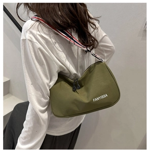 Detail of olive green nylon bag with striped strap and white letter printing