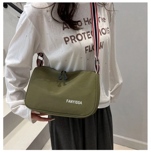 Detail of olive green nylon crossbody bag with wide striped strap and zip closure
