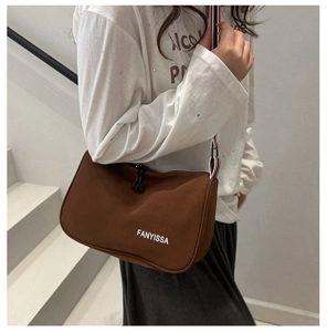 Brown canvas shoulder bag with FANYISSA print and striped webbing strap worn by model